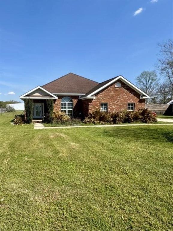 ranch-style home featuring brick siding, fence, and a front lawn