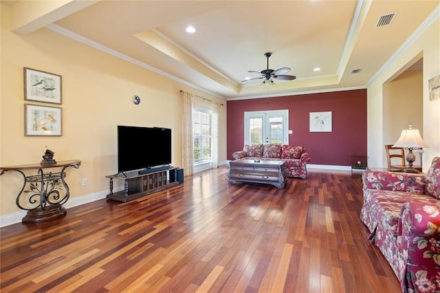 living area featuring crown molding, hardwood / wood-style floors, a raised ceiling, visible vents, and a ceiling fan