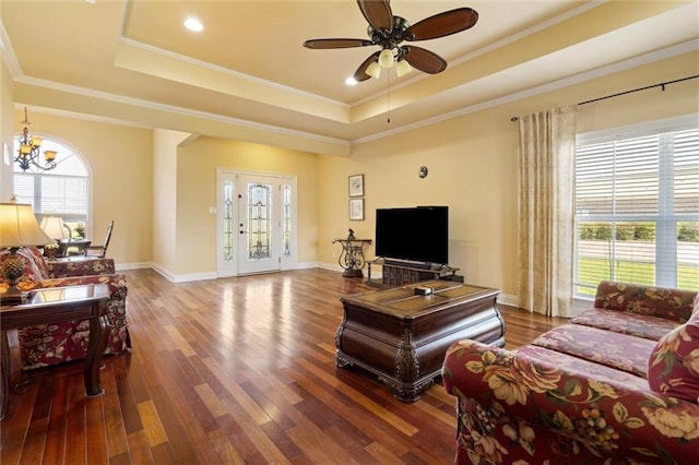 living area featuring a tray ceiling, wood finished floors, and crown molding