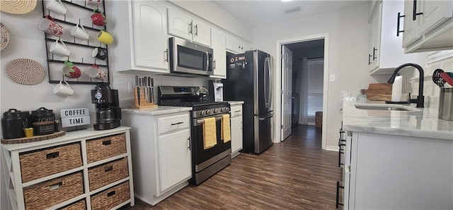 13556 James Copeland Dr, Mobile, AL 36695 - kitchen with appliances with stainless steel finishes, dark wood-style floors, white cabinets, and backsplash