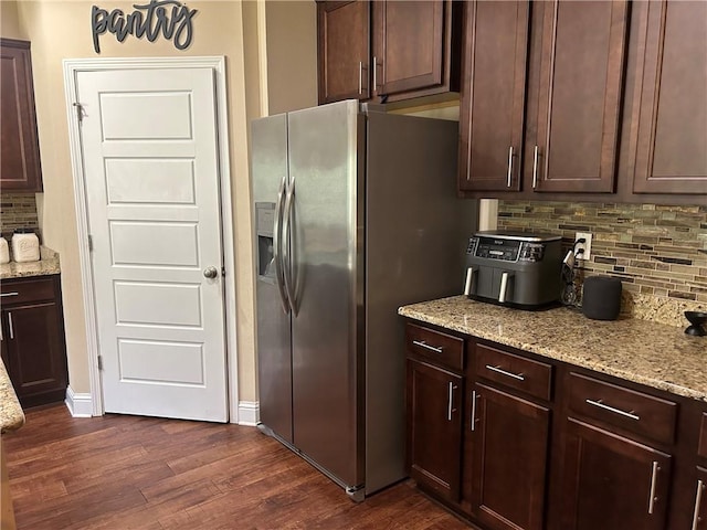 kitchen featuring light stone countertops, dark wood finished floors, decorative backsplash, and stainless steel fridge with ice dispenser