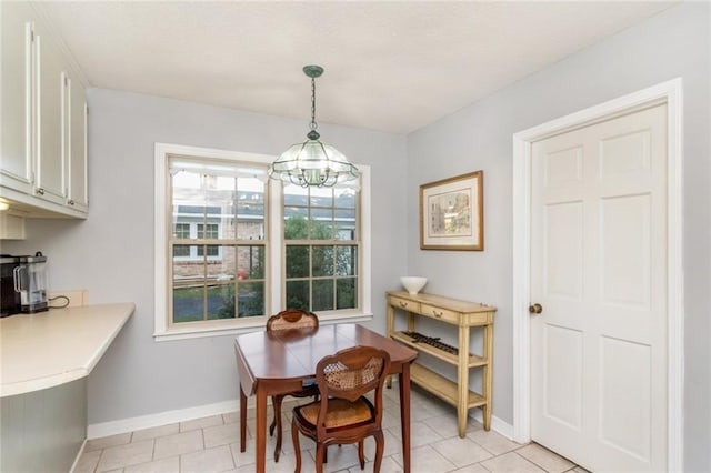 dining area featuring a chandelier, baseboards, and light tile patterned flooring