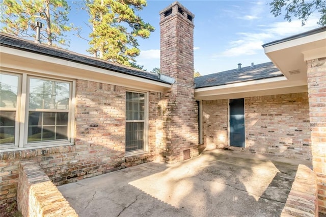 back of property featuring brick siding, a patio, and a chimney