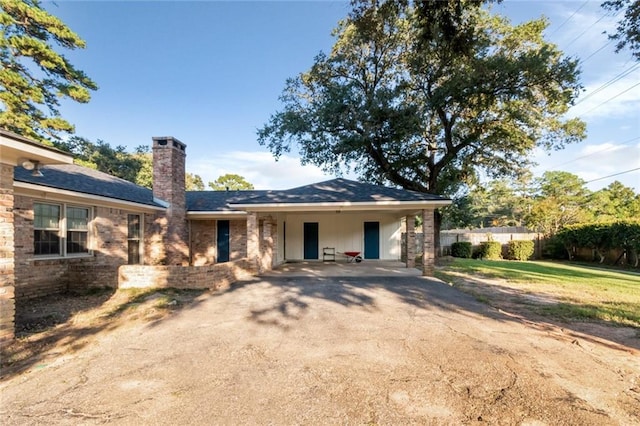 ranch-style house with a carport, a chimney, aphalt driveway, fence, and a front lawn