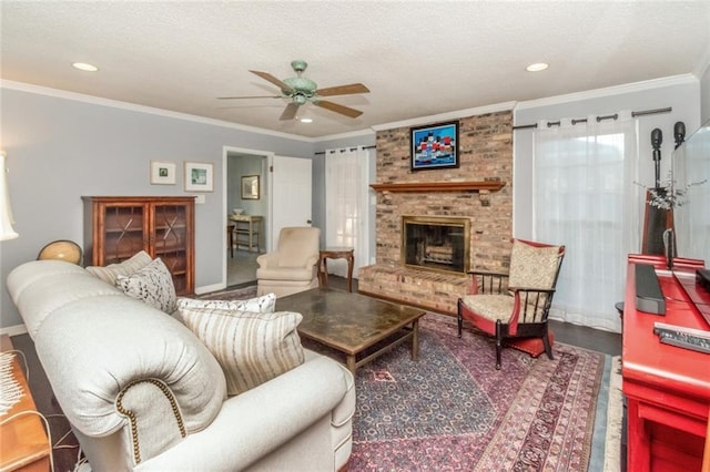 living area with a textured ceiling, crown molding, ceiling fan, and a fireplace