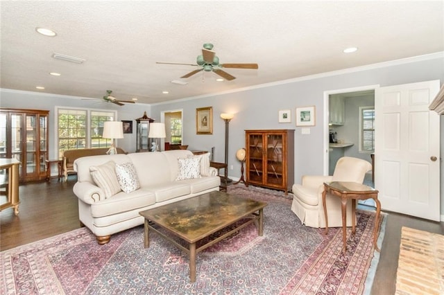 living area featuring a textured ceiling, wood finished floors, ceiling fan, and ornamental molding
