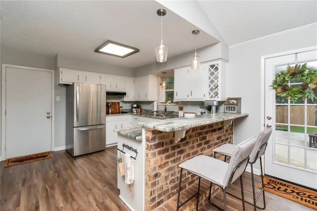 kitchen with white cabinets, wood-type flooring, kitchen peninsula, and stainless steel refrigerator