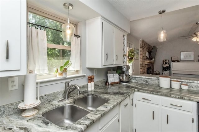 kitchen with decorative light fixtures, ceiling fan, white cabinetry, and sink