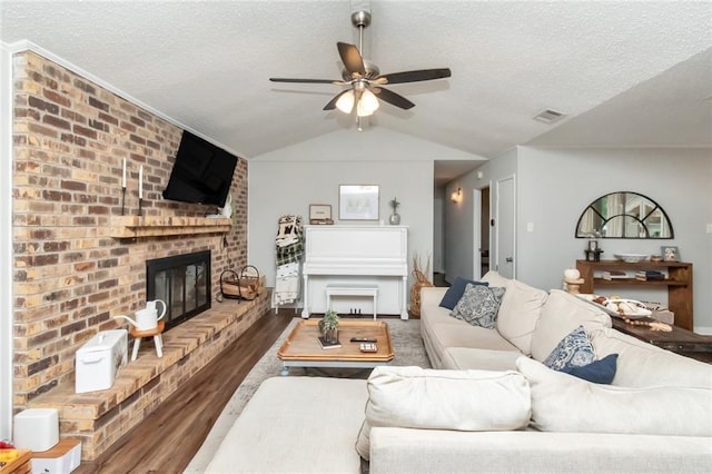 living room featuring ceiling fan, a textured ceiling, vaulted ceiling, a fireplace, and hardwood / wood-style flooring