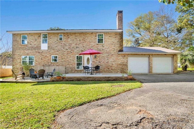 back of property with a lawn, a chimney, aphalt driveway, and brick siding