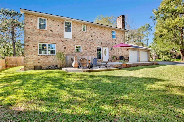 back of property with a yard, a garage, a patio area, and a chimney