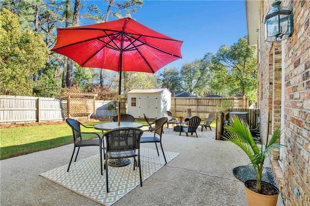view of patio / terrace with a storage unit, a fenced backyard, outdoor dining space, and an outdoor structure
