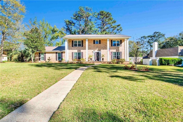 view of front of house featuring metal roof, brick siding, and a front lawn