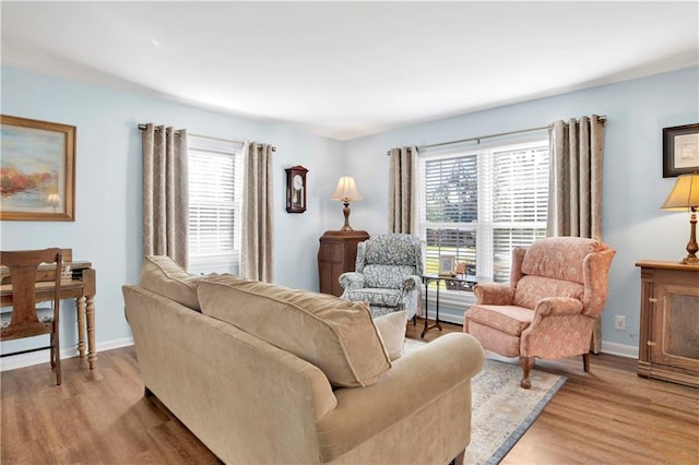living room featuring baseboards, light wood-type flooring, and a wealth of natural light