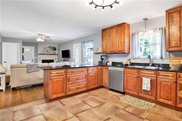 kitchen with stainless steel dishwasher, a sink, brown cabinetry, and plenty of natural light