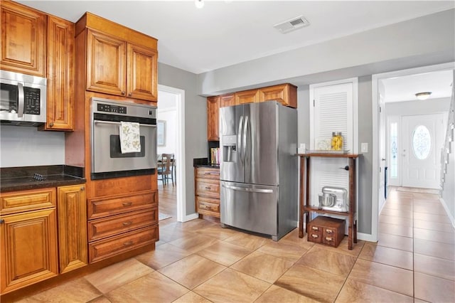 kitchen featuring baseboards, visible vents, appliances with stainless steel finishes, and brown cabinets