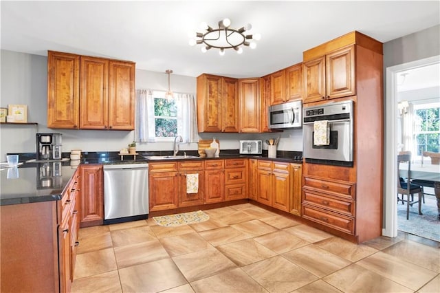 kitchen featuring stainless steel appliances, dark countertops, brown cabinets, and a sink