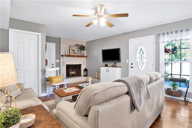living area featuring a ceiling fan, wood finished floors, and a fireplace
