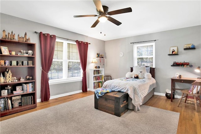 bedroom featuring wood finished floors, baseboards, and multiple windows