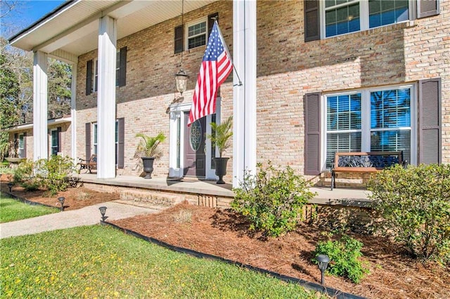 property entrance featuring a porch and brick siding