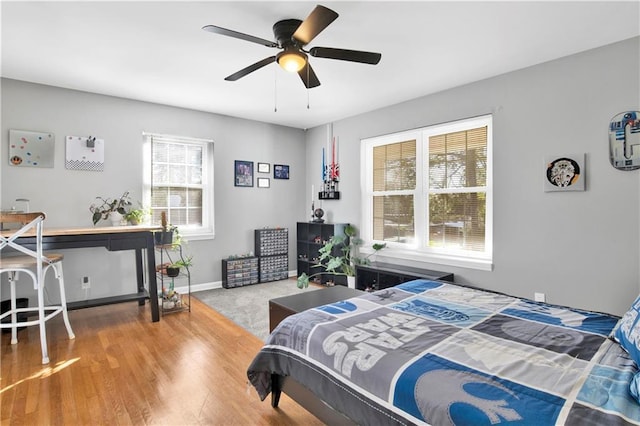 bedroom featuring baseboards, wood finished floors, and ceiling fan