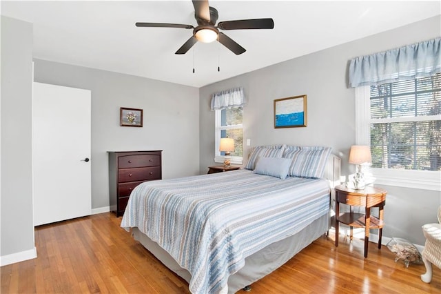 bedroom with ceiling fan, wood finished floors, and baseboards