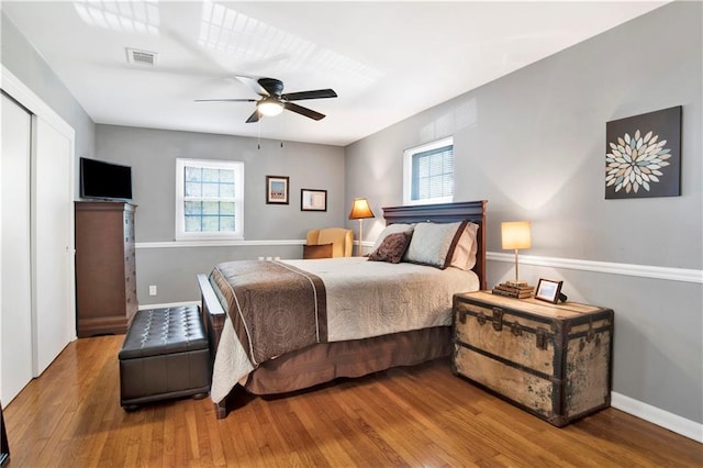 bedroom featuring baseboards, visible vents, wood finished floors, and ceiling fan