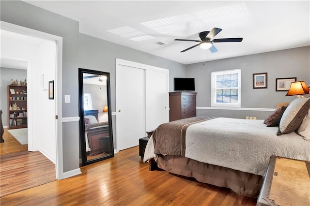 bedroom with a closet, ceiling fan, baseboards, and light wood-style floors