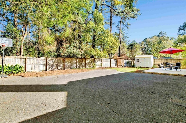 view of yard featuring an outbuilding, a storage unit, a fenced backyard, and a patio area