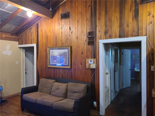 living room with wood walls, baseboards, vaulted ceiling with beams, and wood finished floors