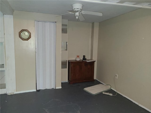 empty room featuring concrete flooring, baseboards, and a ceiling fan