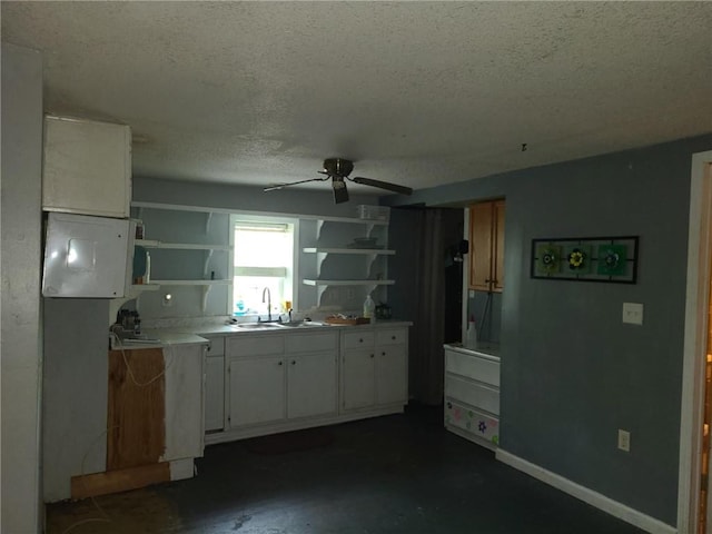 kitchen with baseboards, open shelves, a sink, a ceiling fan, and a textured ceiling