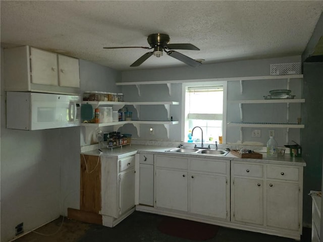 kitchen featuring a sink, white microwave, open shelves, and white cabinets