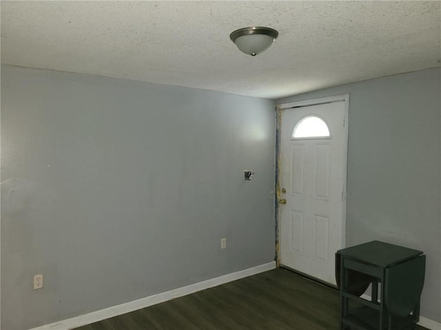 foyer featuring a textured ceiling, baseboards, and dark wood finished floors