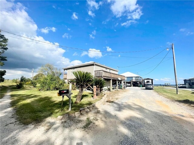 raised beach house featuring driveway, a front lawn, and a deck