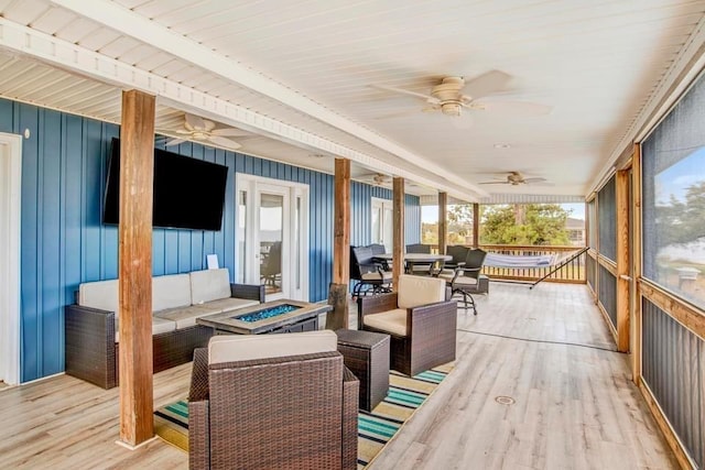 sunroom / solarium featuring outdoor dining area, an outdoor living space with a fire pit, and ceiling fan