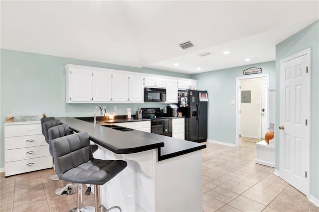 kitchen featuring light tile patterned floors, a peninsula, a sink, and black appliances