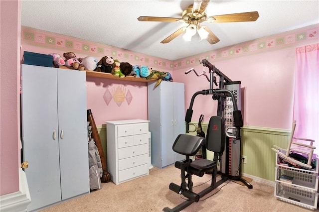 exercise area featuring ceiling fan, light carpet, and a textured ceiling