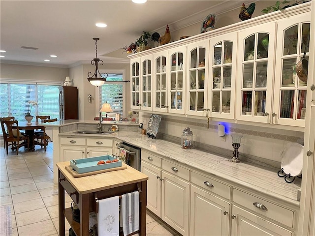 9849 Aspen Cir, Daphne, AL 36527 - kitchen featuring a peninsula, ornamental molding, light tile patterned floors, hanging light fixtures, and glass insert cabinets