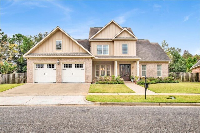 craftsman-style house featuring driveway, fence, a front lawn, and french doors