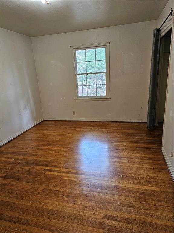 unfurnished room with dark wood-type flooring