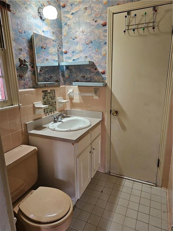 bathroom featuring tile patterned flooring, vanity, toilet, and tile walls