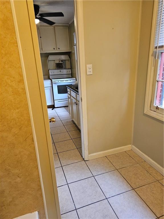 corridor featuring light tile patterned floors and ornamental molding