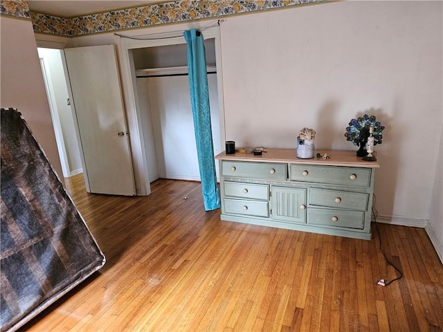 bedroom with light hardwood / wood-style floors and a closet