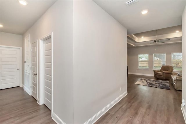 corridor featuring dark hardwood / wood-style flooring and a tray ceiling