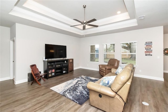 living room featuring ceiling fan, a raised ceiling, wood-type flooring, and crown molding