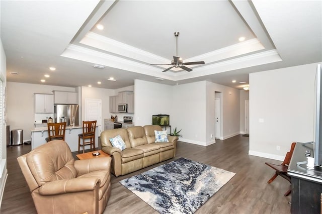 living room with a tray ceiling, ceiling fan, hardwood / wood-style floors, and ornamental molding