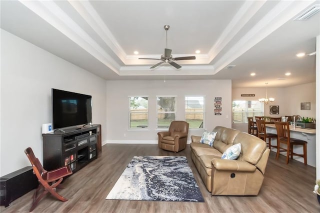 living room featuring hardwood / wood-style floors, ceiling fan with notable chandelier, a raised ceiling, and crown molding