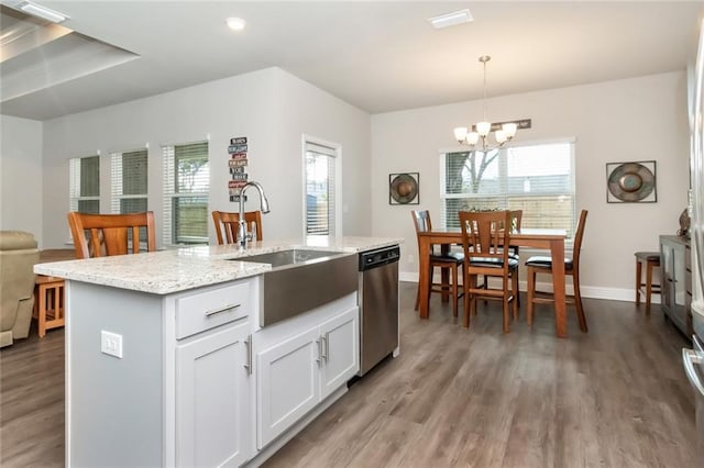 kitchen with white cabinets, decorative light fixtures, a notable chandelier, dishwasher, and an island with sink