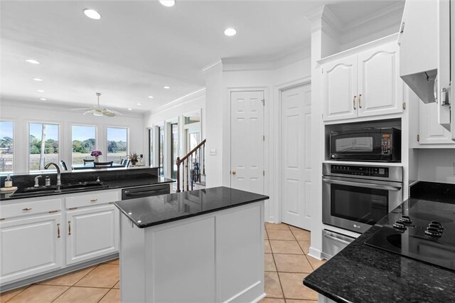 kitchen with black appliances, ornamental molding, light tile patterned floors, and a sink